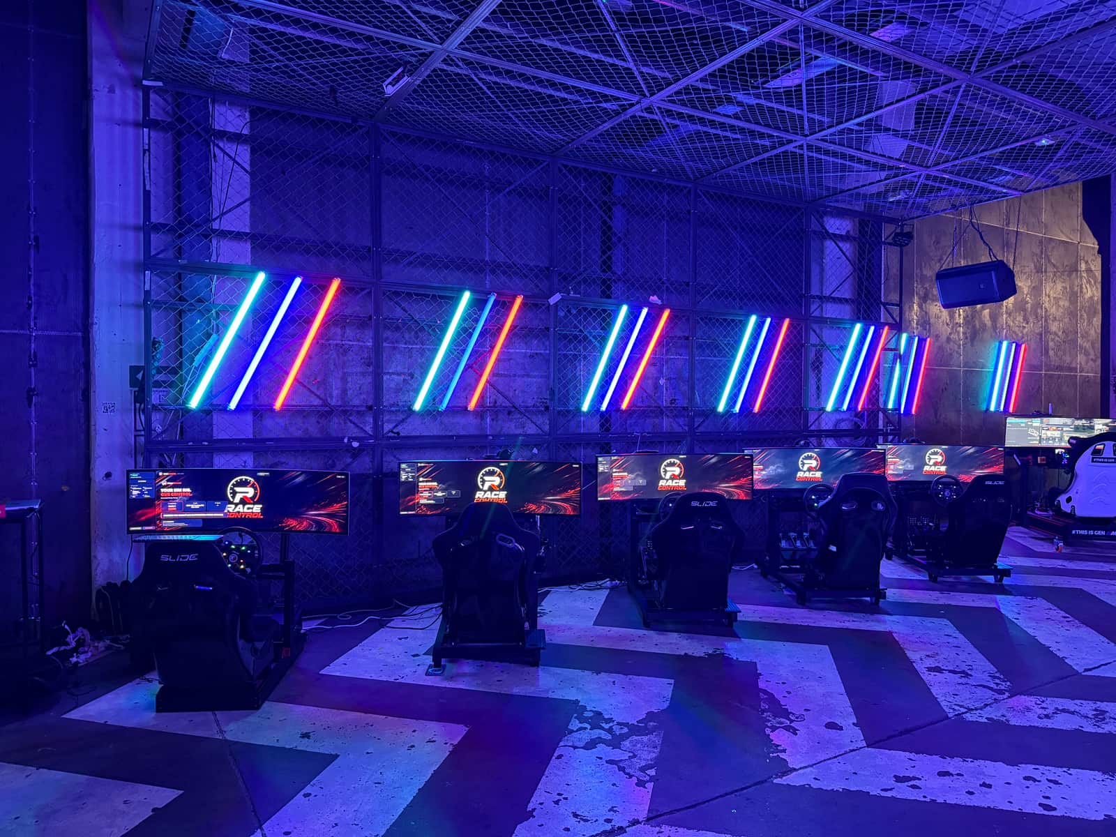A row of simulators under neon tubes at the BMW M Festival stand in Gdańsk